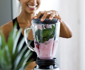 Woman making smoothie after dental implant surgery in Washington DC