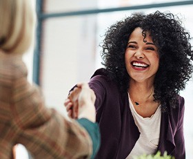 Woman in business casual with beautiful smile shaking professional’s hand