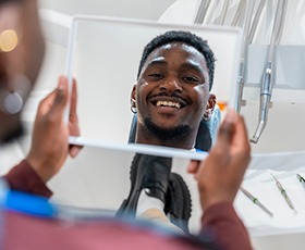 A man looking in the mirror at his smile