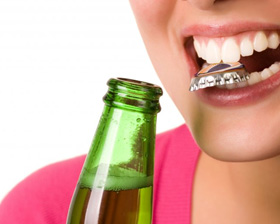 Woman opening a bottle with her teeth