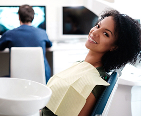 A young woman seated in the dentist’s chair waiting for her dentist to examine her X-rays and determine if she needs a dental crown