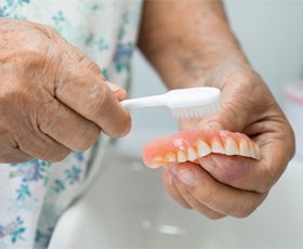 a person in Washington brushing their dentures clean 