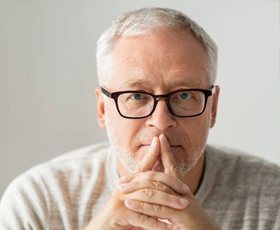 An older man covering his mouth