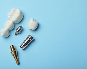The parts of a dental implant and bridge on a light blue background