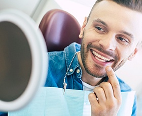 Man admiring his new smile after getting dental implants in Washington DC