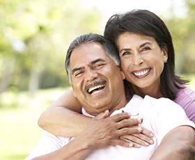 Smiling couple with dental implants in Washington laughing outside