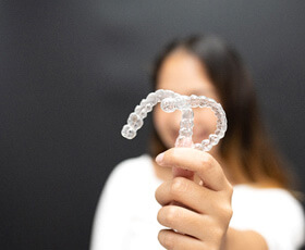 smiling patient holding up clear aligners