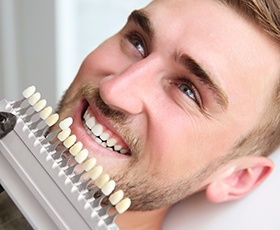 Man's smile compared with tooth color chart