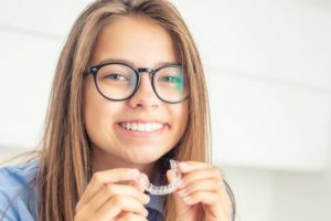 Woman smiling with Invisalign trays 