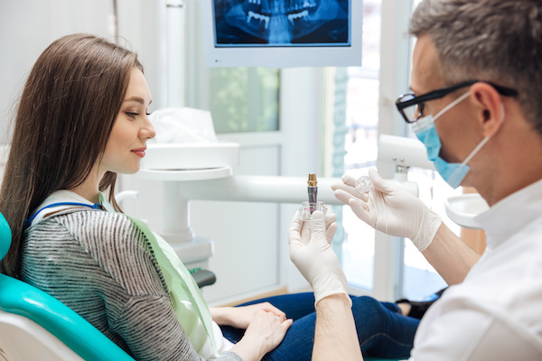 male dentist showing female patient dental implant